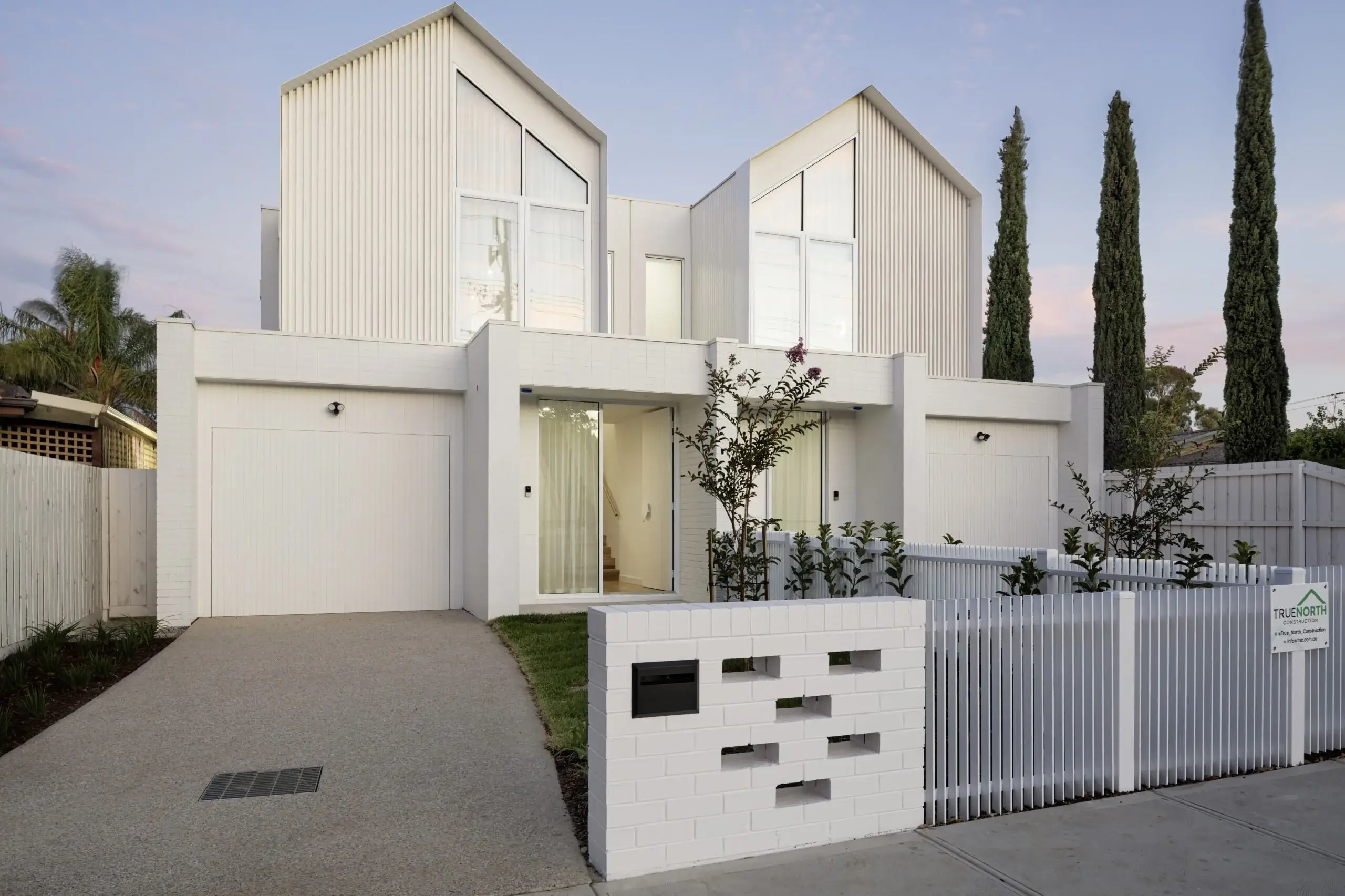 Twin-gabled white facade of the Wingara dual occupancy at dusk